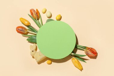 Blank greeting card, beautiful tulip flowers, Easter bunny and painted eggs on beige background