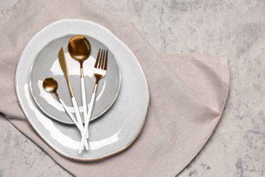 Plates with set of cutlery on grey grunge background