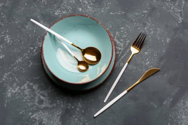 Bowl, plate and set of cutlery on grey grunge background