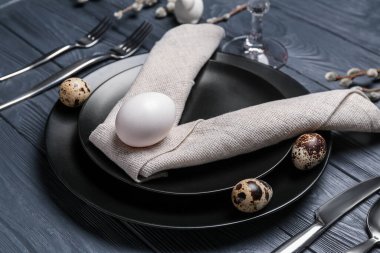 Table setting with Easter eggs on dark wooden background, closeup