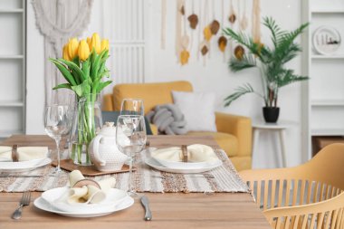 Table setting for International Women's Day celebration with tulip flowers and teapot in interior of room
