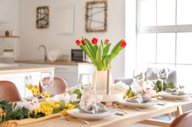 Beautiful table setting for International Women's Day celebration with different flowers in interior of light room