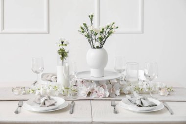 Beautiful table setting for International Women's Day celebration with eustoma and orchid flowers in light room