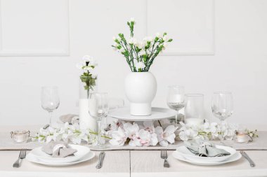 Beautiful table setting for International Women's Day celebration with eustoma and orchid flowers in light room