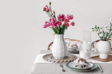 Beautiful table setting for International Women's Day celebration with flowers and burning candles in dining room