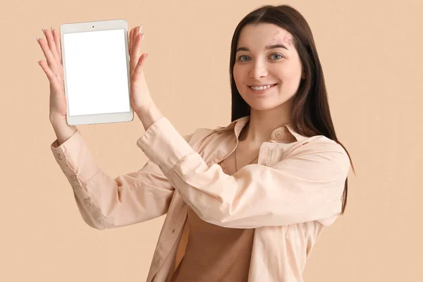Young woman with tablet computer on beige background
