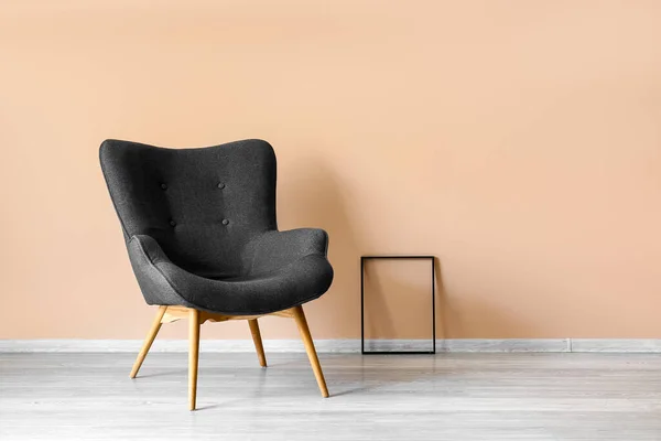 Stylish grey armchair and frame near beige wall