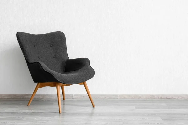 Stylish grey armchair near white wall