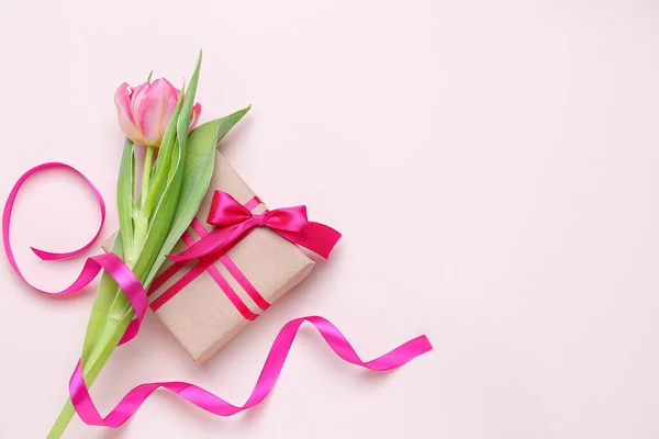 Beautiful tulip flower and gift for Women's Day celebration on color background