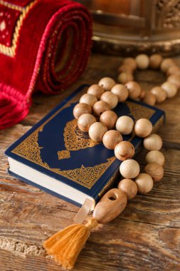 Koran with prayer beads for Ramadan on wooden table, closeup