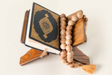 Rehal with Koran and prayer beads for Ramadan on light background