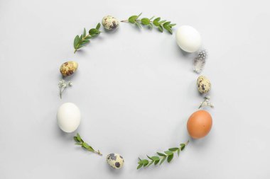 Frame made of Easter eggs and eucalyptus branches on grey background