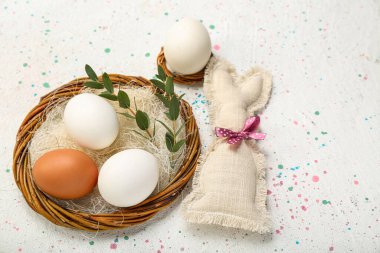 Nest with Easter eggs, eucalyptus branches and bunny on white background