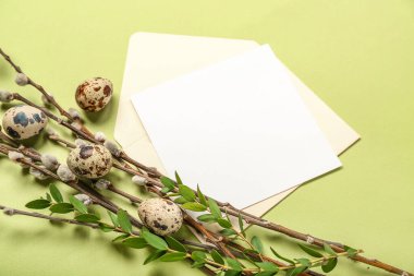 Blank greeting card, Easter eggs and plant branches on green background