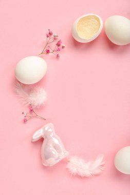 Frame made of Easter eggs and gypsophila flowers on pink background