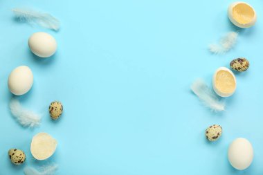 Frame made of Easter eggs  and feathers on blue background
