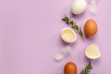 Composition with Easter eggs, feathers and eucalyptus branches on lilac background