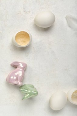 Frame made of Easter eggs and bunnies on grey background