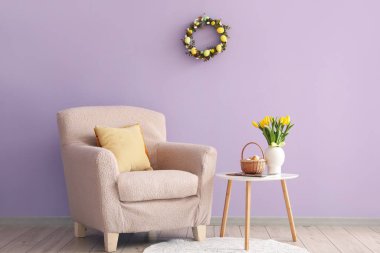 Interior of living room with Easter wreath, armchair and table