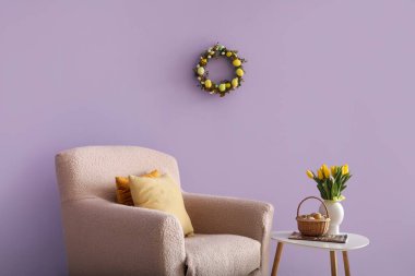Interior of living room with Easter wreath, armchair and table