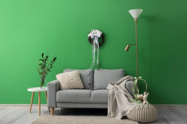 Interior of living room with sofa and Easter wreath on green wall