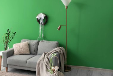 Interior of living room with sofa and Easter wreath on green wall