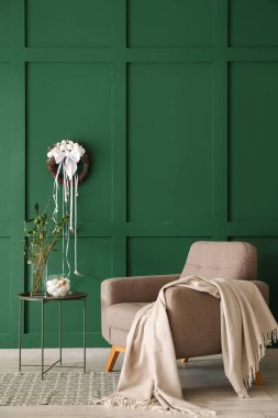 Interior of stylish room with Easter wreath, armchair and table