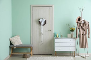 Interior of hall with Easter wreath on light wooden door