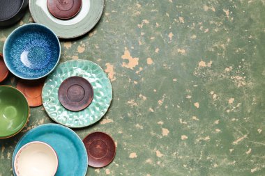 Composition with clean ceramic plates and bowls on green grunge background