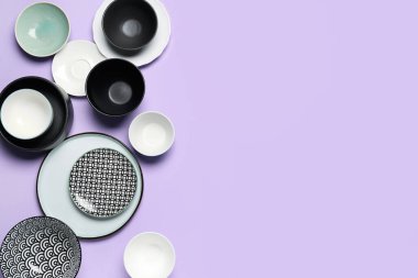 Composition with clean ceramic plates and bowls on lilac background