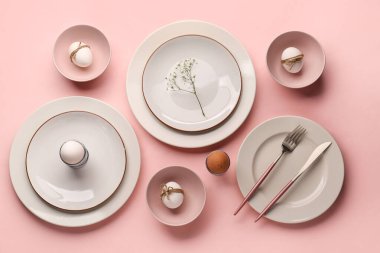 Composition with crockery, Easter eggs and gypsophila flowers on pink background