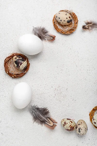 Frame made of Easter eggs and feathers on white grunge background