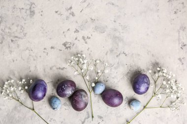 Composition with painted Easter eggs and gypsophila flowers on light background