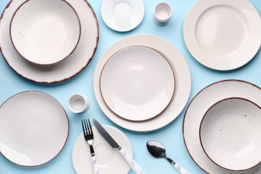 Set of plates with cutlery on blue background