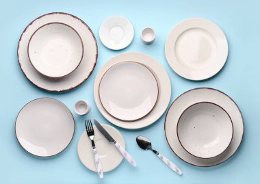 Set of plates with cutlery on blue background