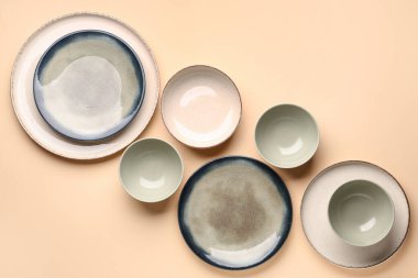 Set of plates and bowls on beige background