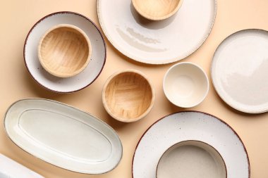 Set of plates and bowls on beige background