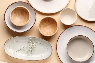 Set of plates and bowls with gypsophila flowers on beige background