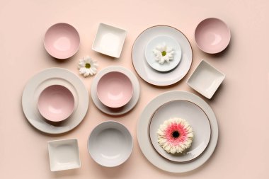 Set of plates and bowls with chrysanthemum flowers on beige background