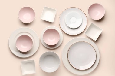 Set of plates and bowls on beige background