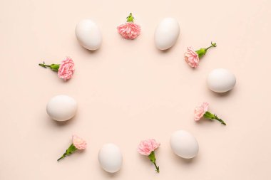 Frame made of Easter eggs and carnation flowers on pink background