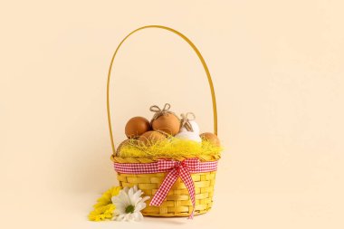 Wicker basket with Easter eggs and chrysanthemum flowers on white background