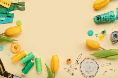 Frame made of tailor's supplies and tulips on yellow background. Hello spring