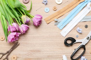 Frame made of tailor's supplies and tulips on wooden background. Hello spring
