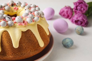 Tasty Easter cake, eggs and tulip flowers on light background, closeup