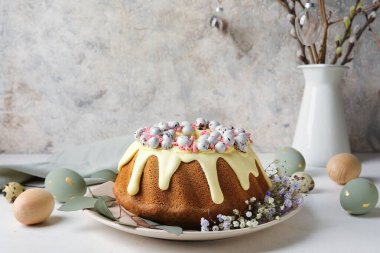 Plate with tasty Easter cake, eggs and gypsophila flowers on light table