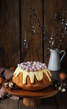 Dessert stand with tasty Easter cake, eggs and willow branches on wooden table
