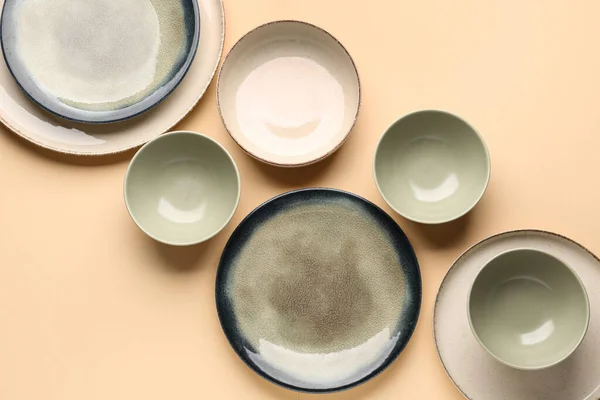 Set of plates and bowls on beige background
