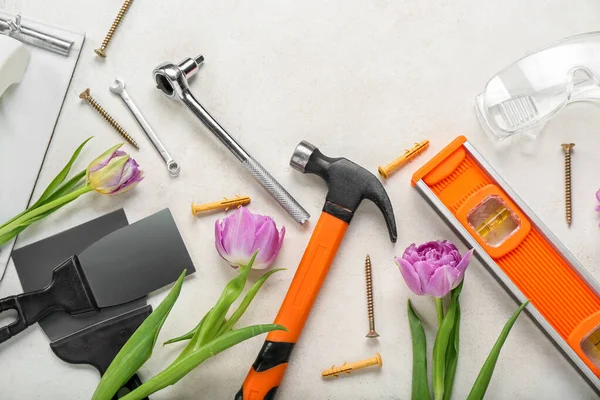 Builder's tools with tulips on white background. Hello spring