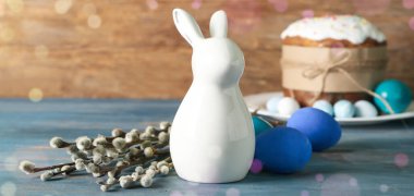 Ceramic bunny, Easter eggs and pussy willow branches on wooden table